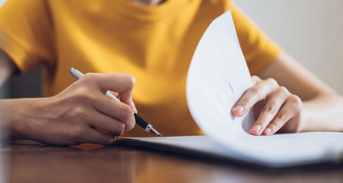 woman in yellow shirt holding a pen and paper