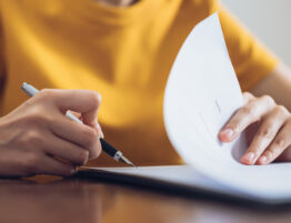 woman in yellow shirt holding a pen and paper